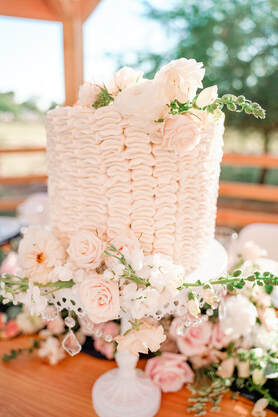 Picture - of a 8 inch round cake with vertical ruffles, decorated with roses and greenery.